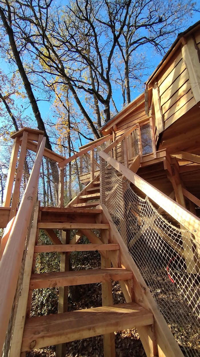 Montée d'escalier avec du filet tendu cabane sur pilotis/ cabane dans les arbres/ insolite
